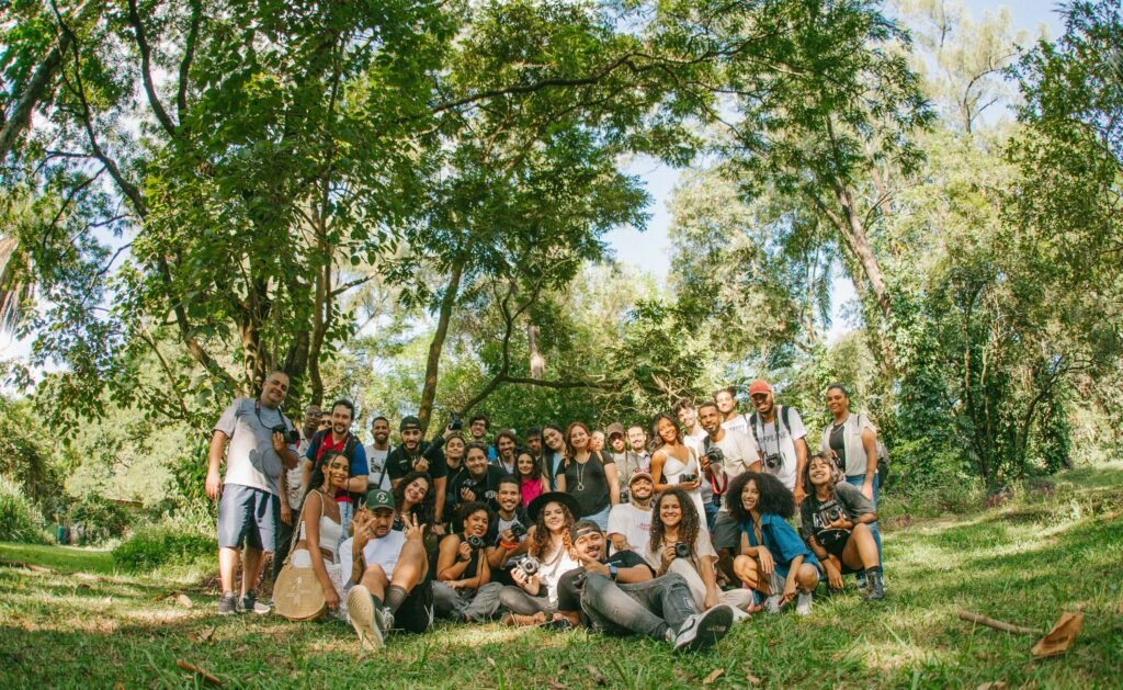 A diverse group of joyful people posing together outdoors in a sunny park setting.